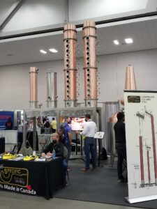 A booth set up at a trade show, showing a distilling set up.