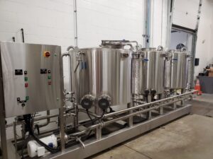 A row of three distilling tanks with a large control panel.
