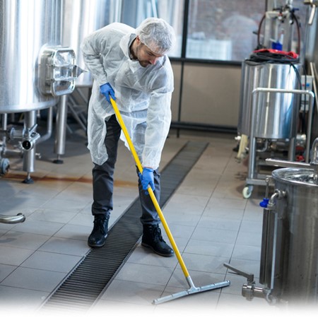 A man mops the floor in a brewery.
