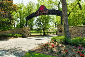 A brick wall with a driveway and overhanging sign that reads Gervasi Vinyards.