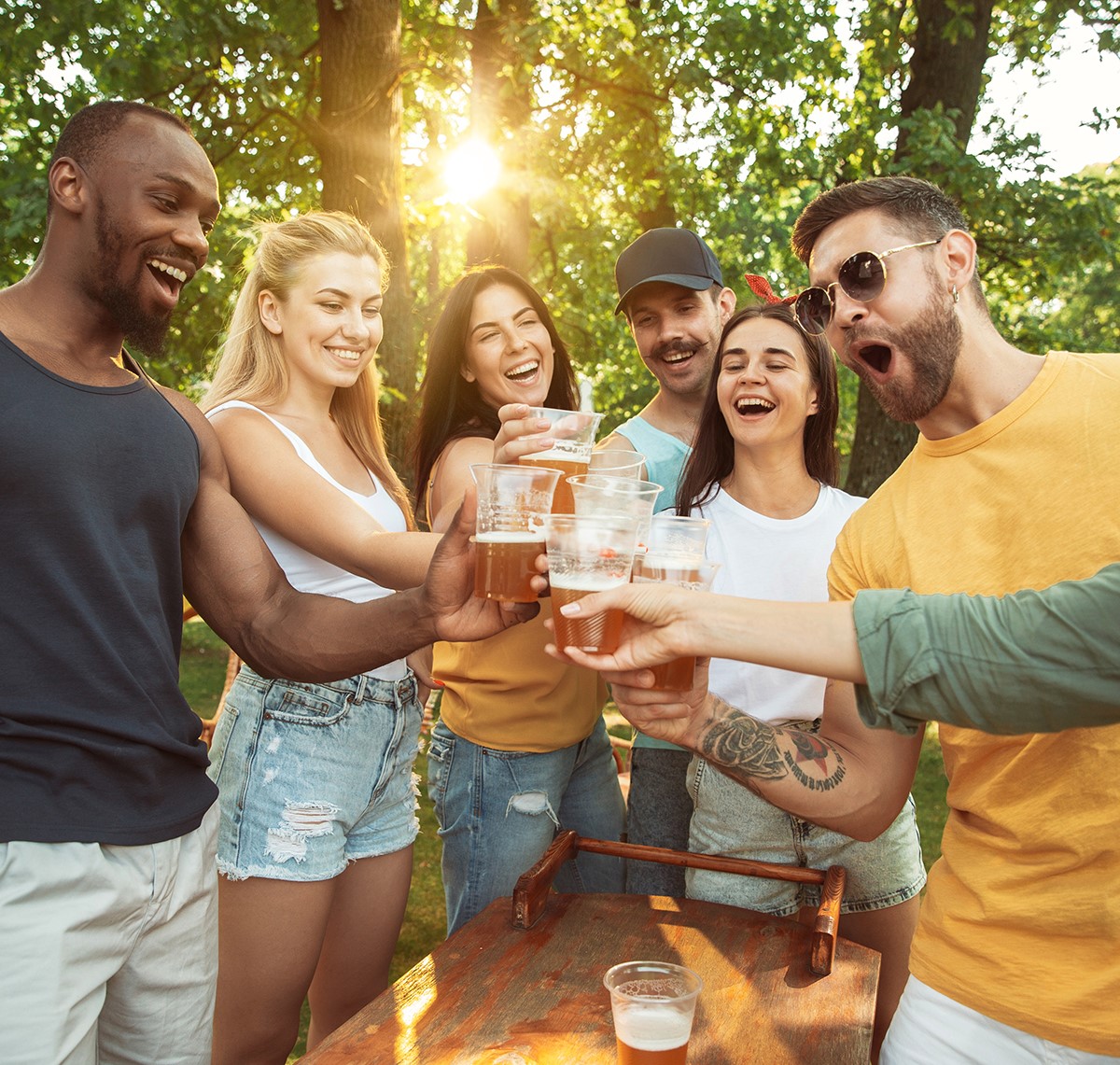 A group of people stand with beer glasses together smiling.